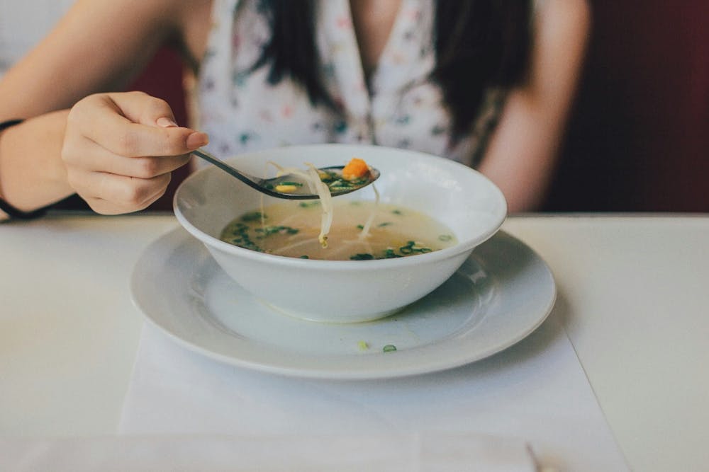  A woman having soup in a white bowl