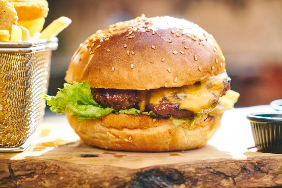 Bucket of fries placed next to a burger