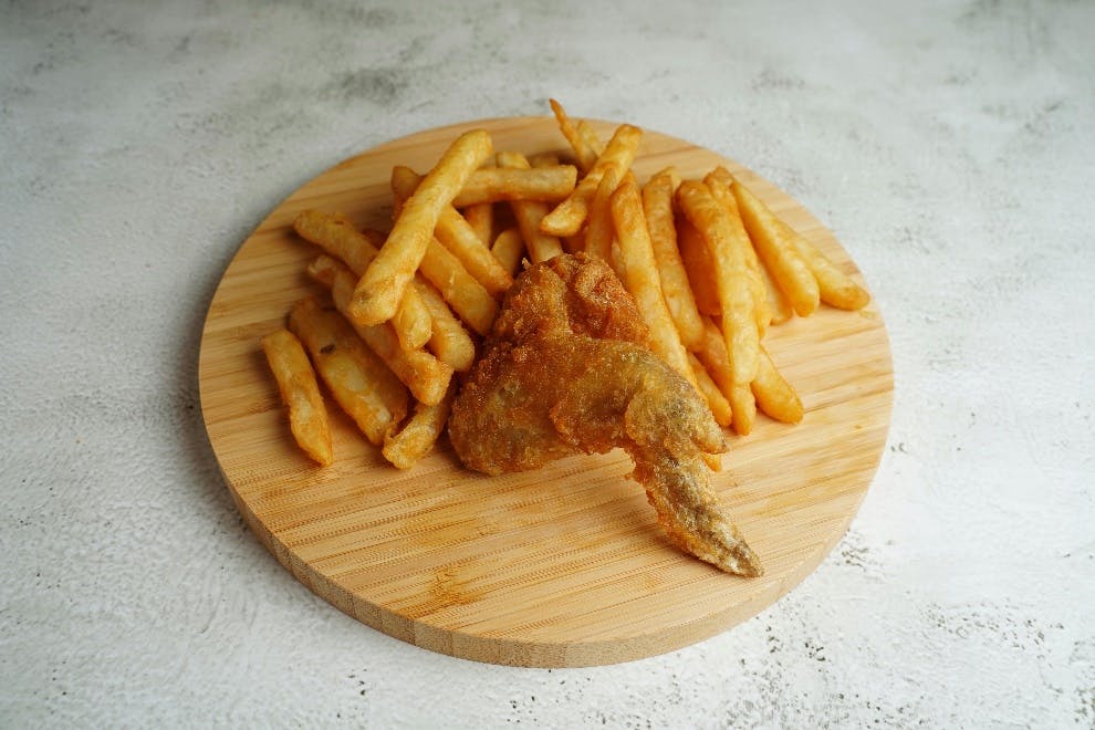 Single chicken wing placed between French fries