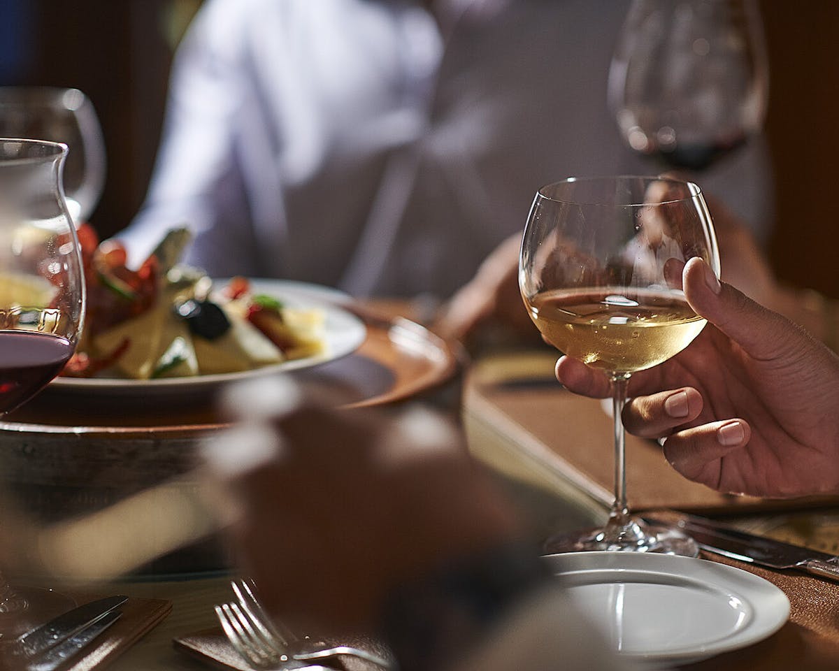 a person sitting at a table with wine glasses