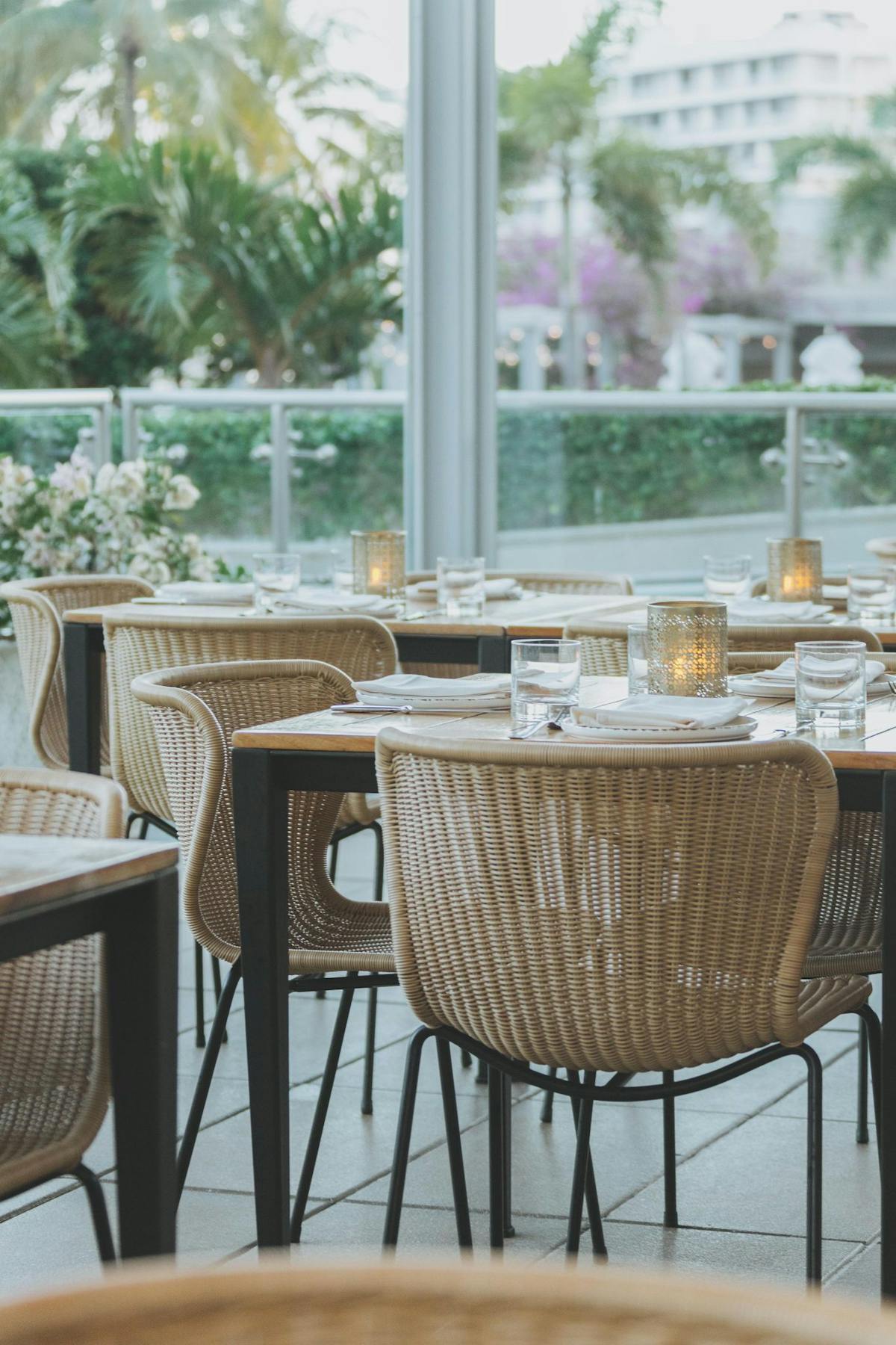 a dining room table with wicker chairs in front of a window at Edge Steak & Bar, Miami