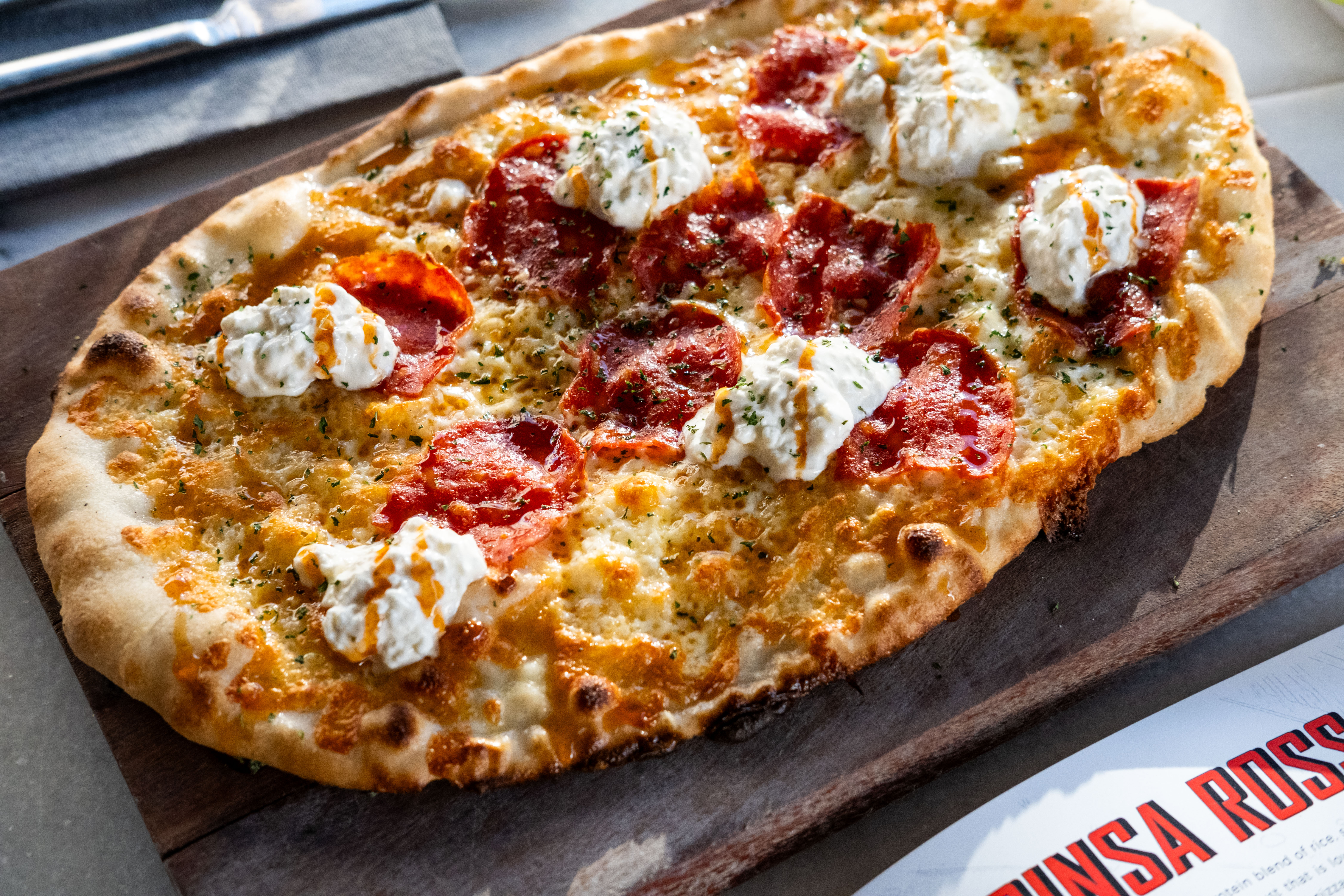 a pizza sitting on top of a wooden cutting board