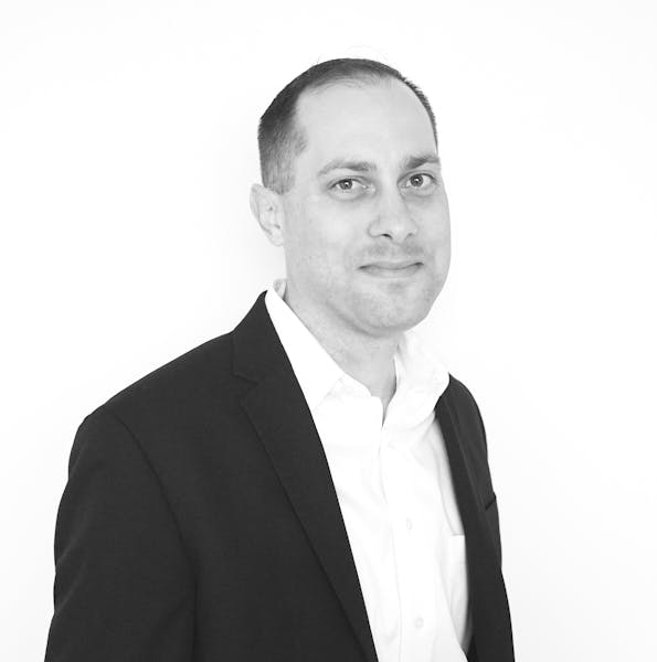 a man wearing a suit and tie smiling at the camera
