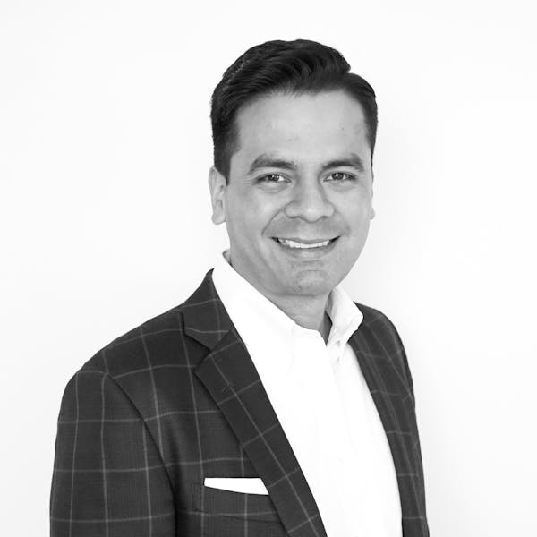 a man wearing a suit and tie smiling at the camera