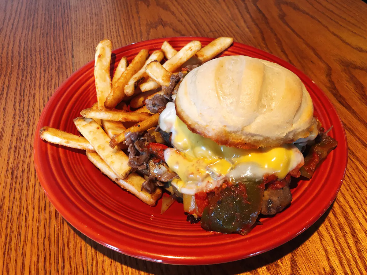 a red plate topped with a sandwich and fries on a table