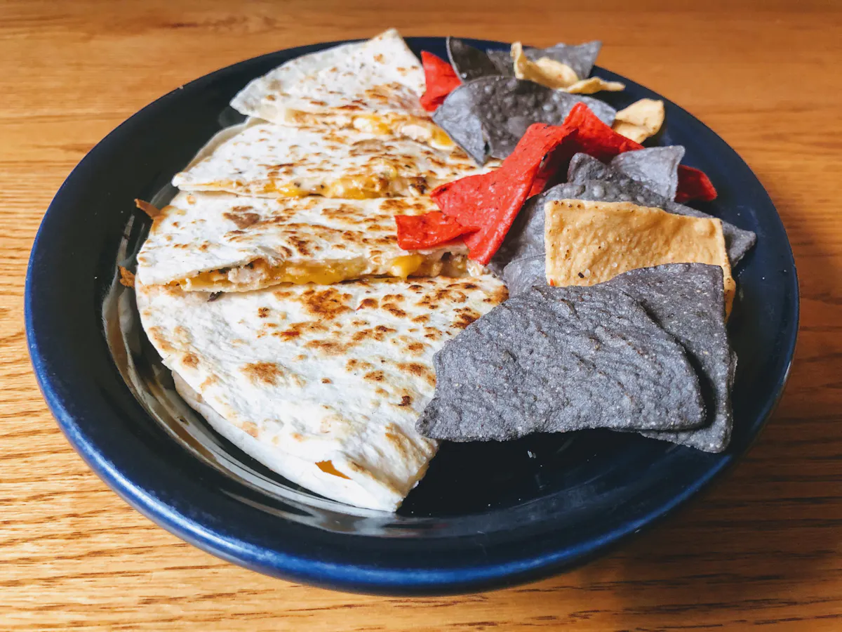 a plate of food with a slice of pizza on a wooden table