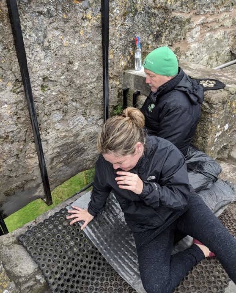 a man and a woman sitting on a rock with Blarney Stone in the background