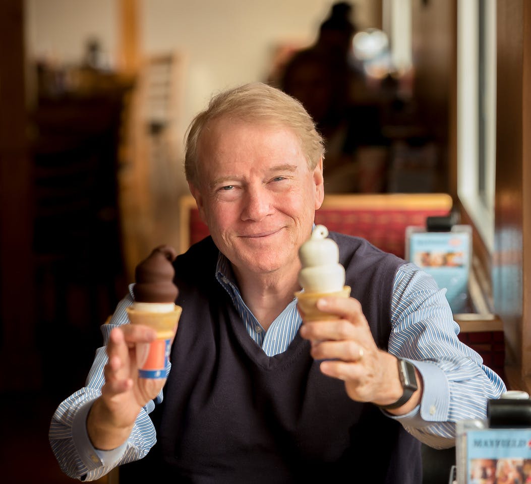 a person holding two ice cream cones