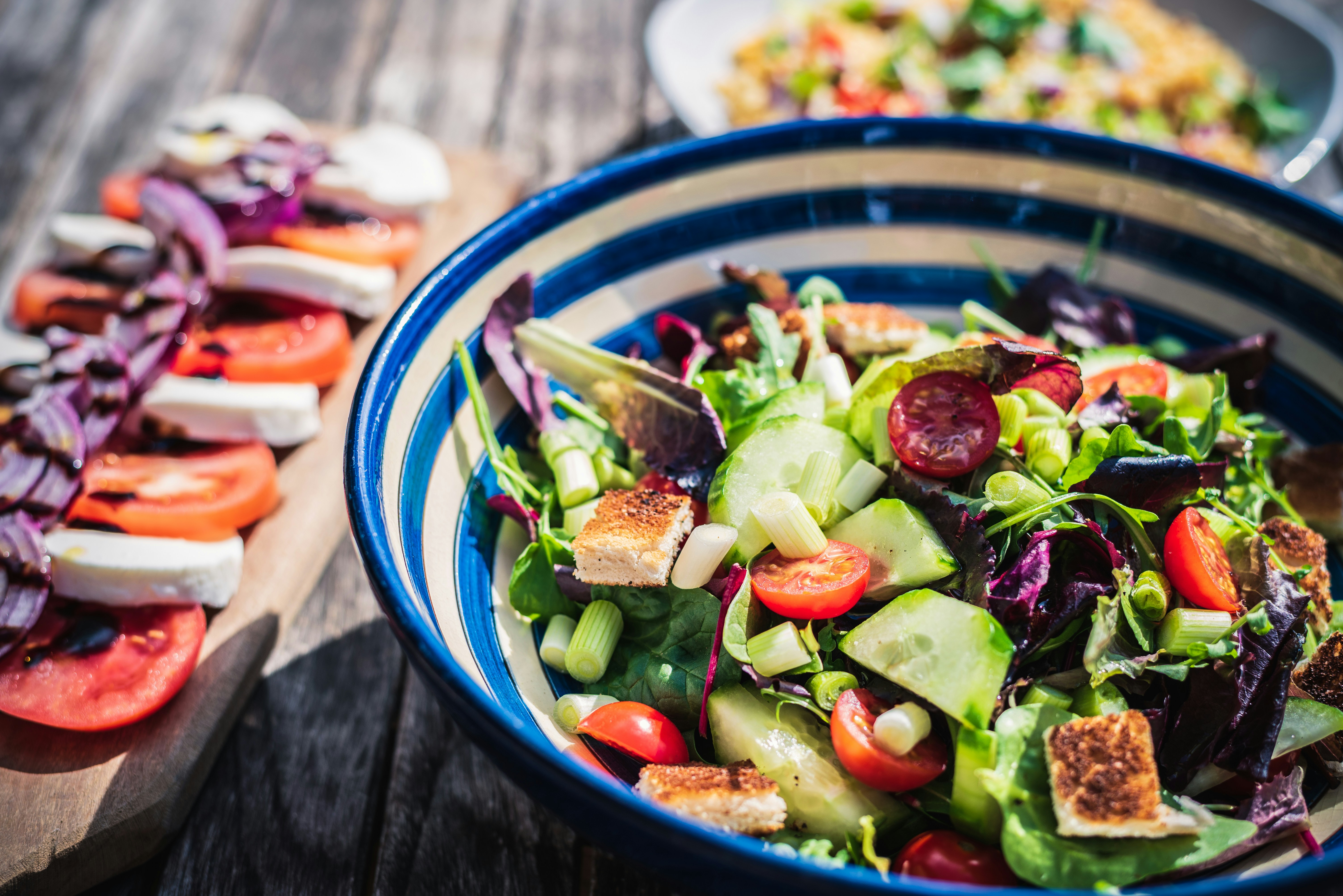 a bowl of salad next to a plate of food