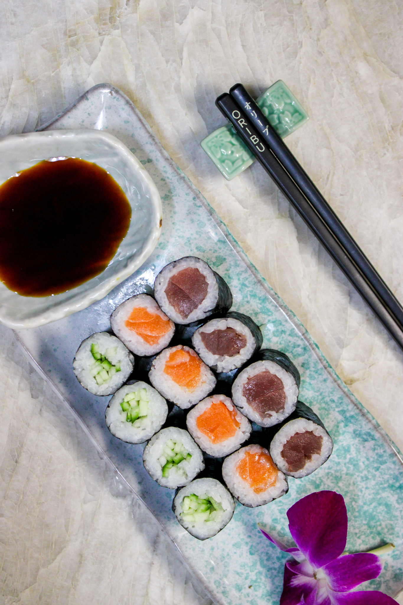 a plate of sushi with chopsticks and soy sauce