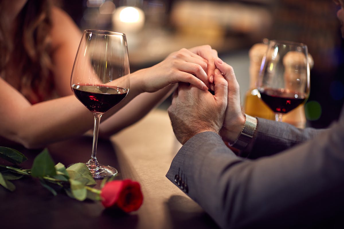 couple holding hands with wine