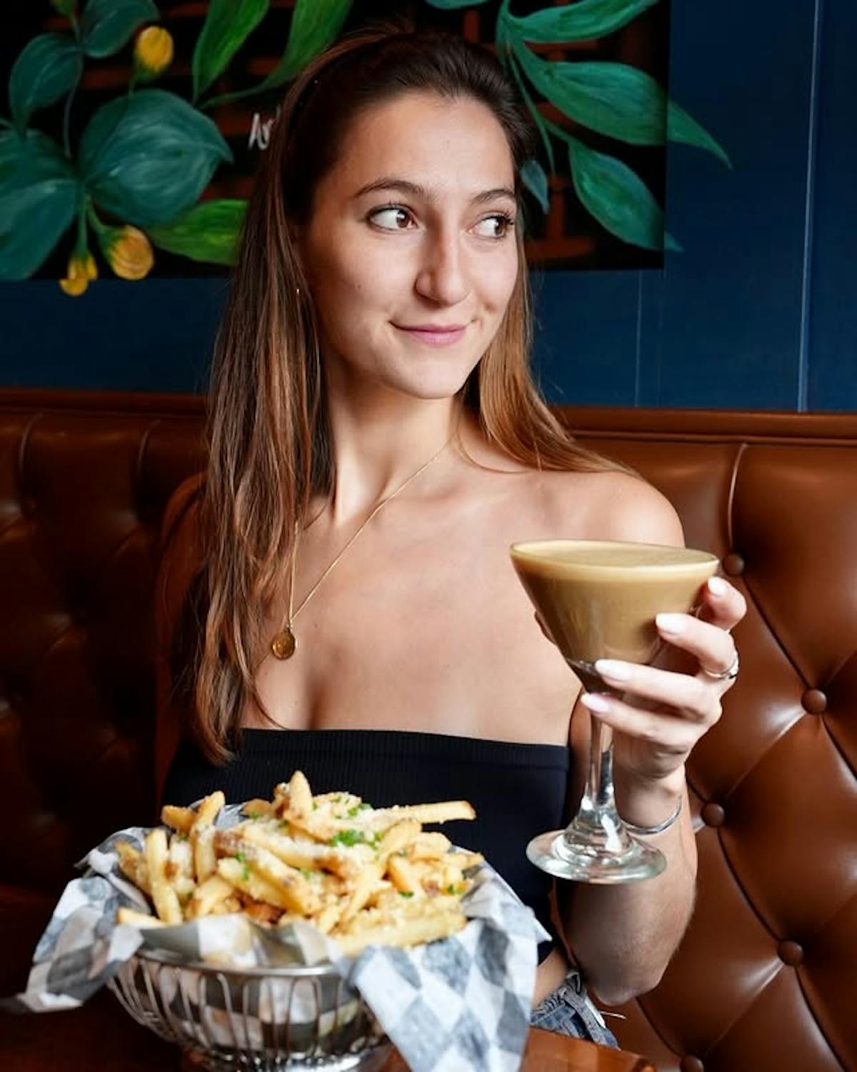 woman holding espresso martini with truffle fries