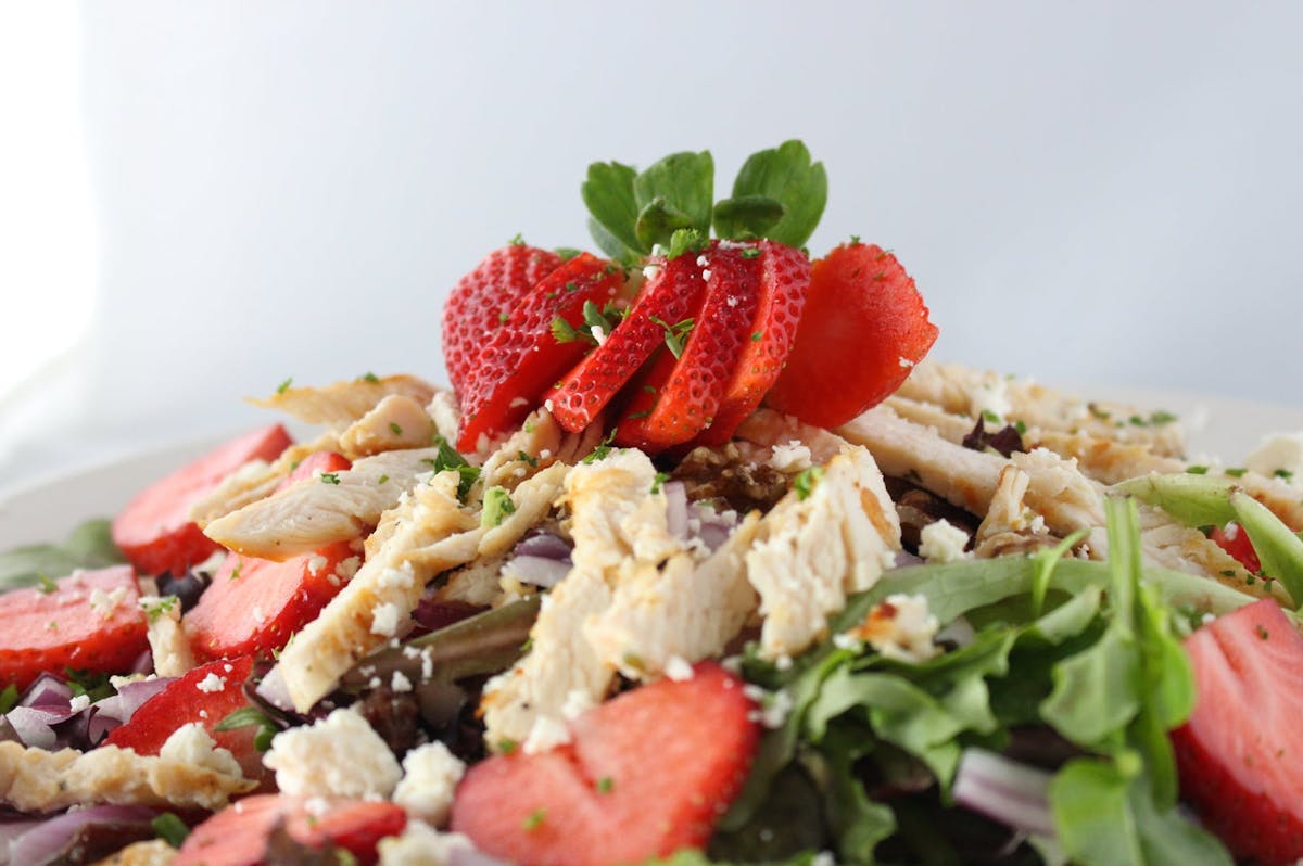 a dish is filled with salad topped with strawberry