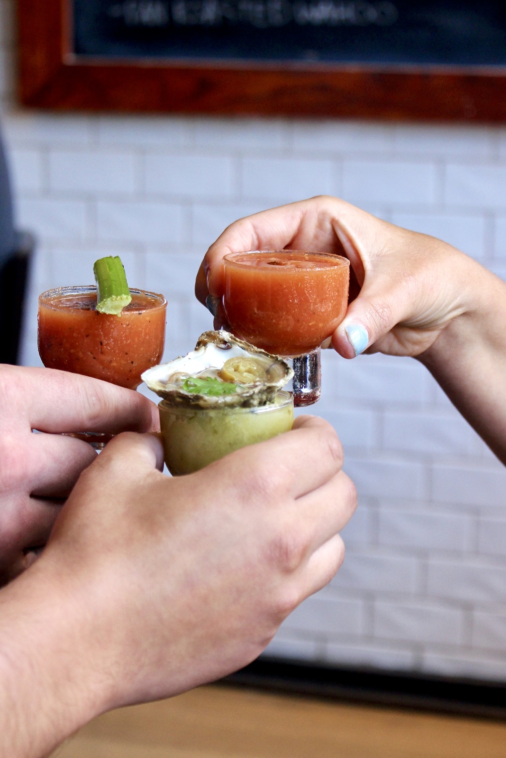 a group of hands holding small glasses of food