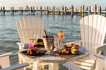 Seafood sandwich and fries with a champagne bucket and a tropical cocktail overlooking the turquoise bay.