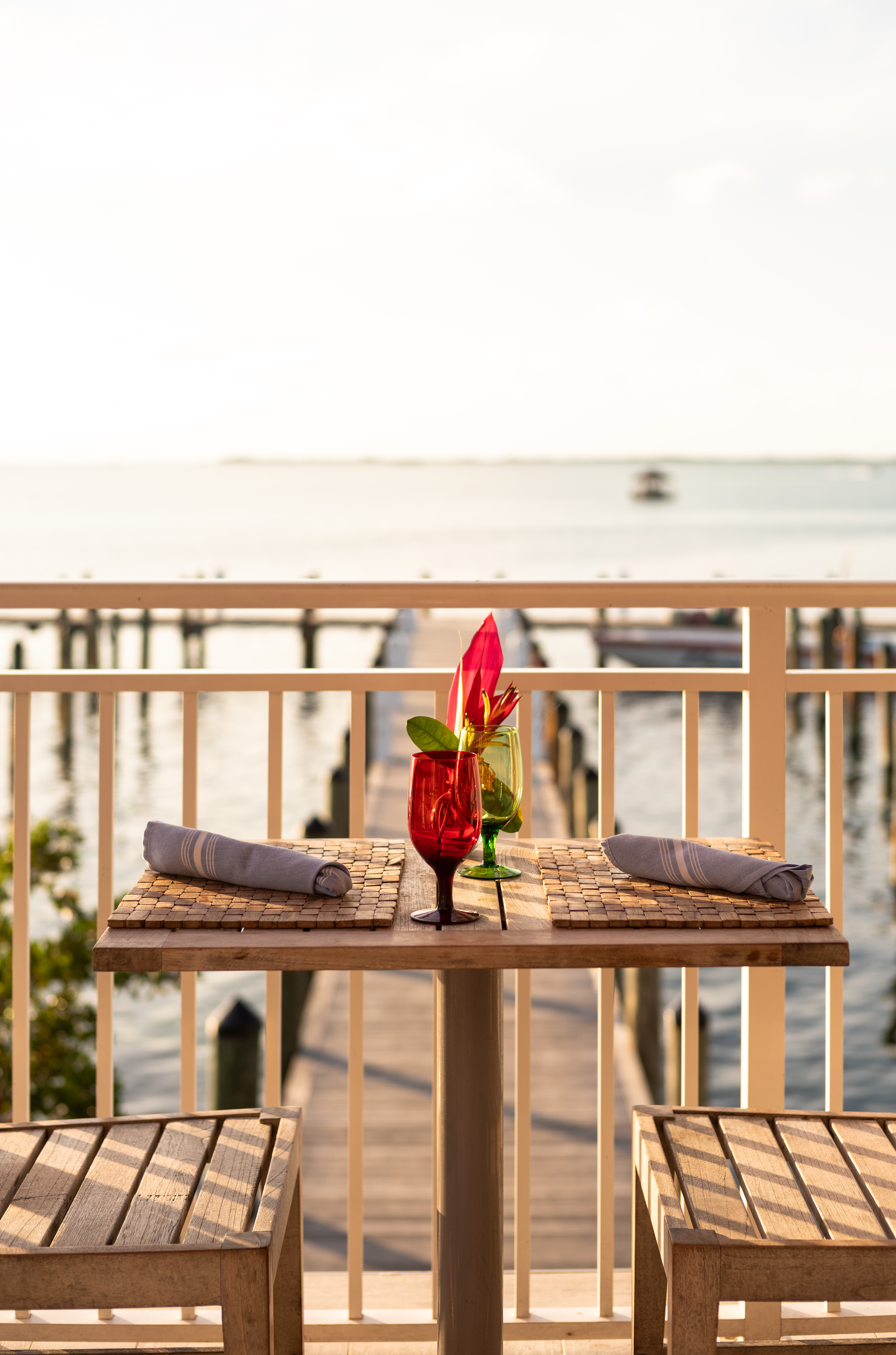 Two-person waterfront table with tropical drinks and sunset views over the dock and ocean at Sol by the Se