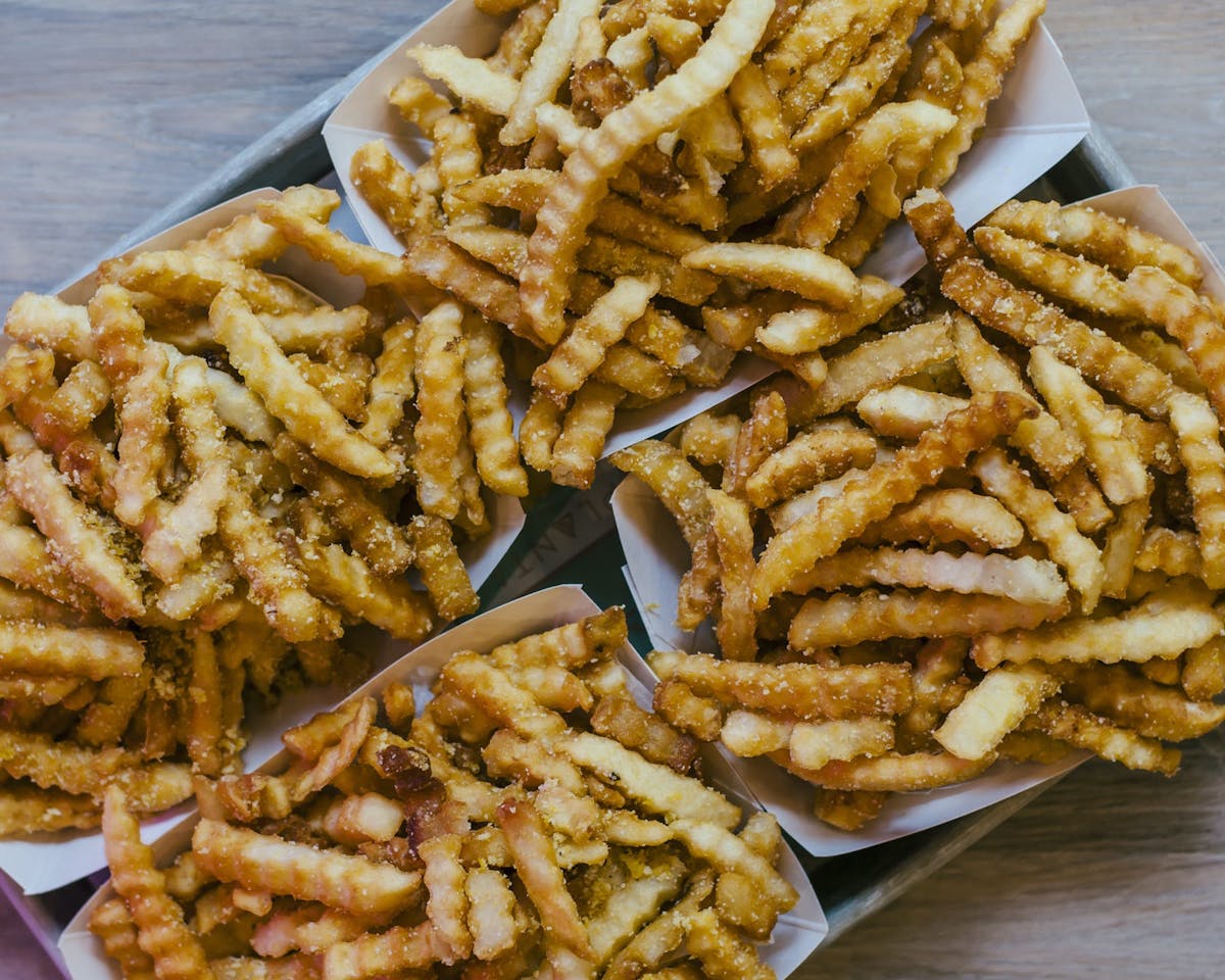 a hot dog on a bun sitting on top of a pile of fries