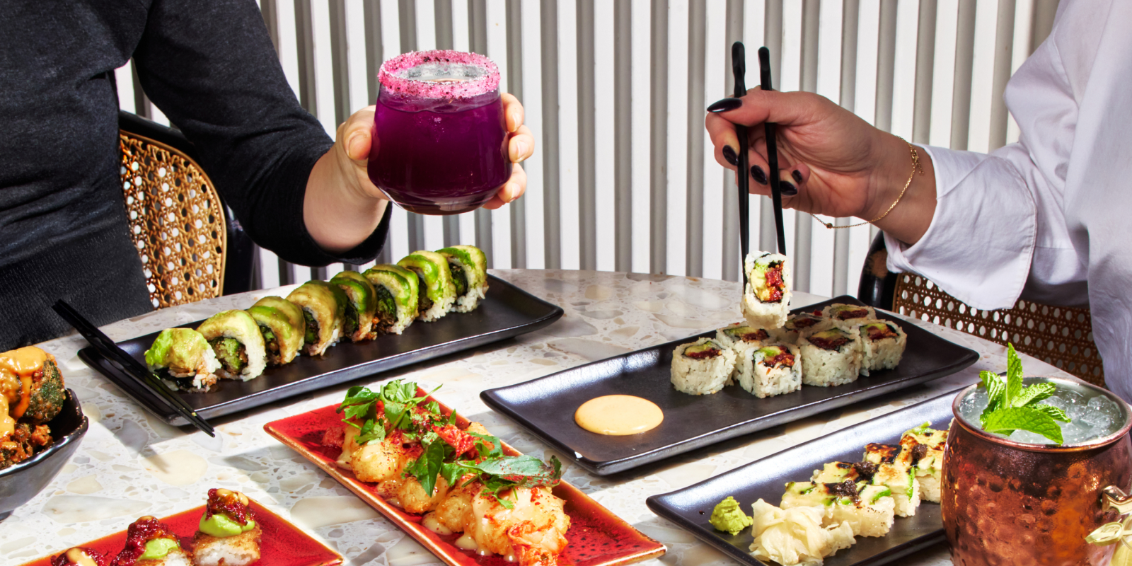 a person holding a plate of food on a table