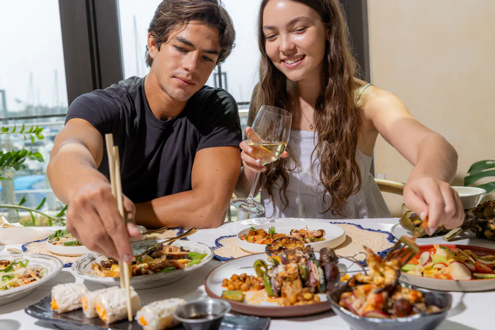 a man and woman sitting at a table with food