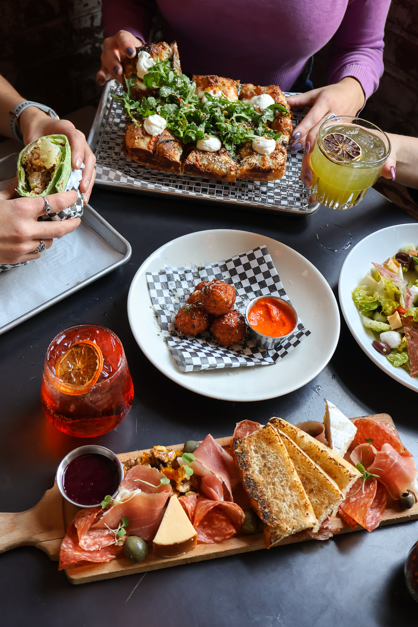 a woman holding a bunch of food on a table