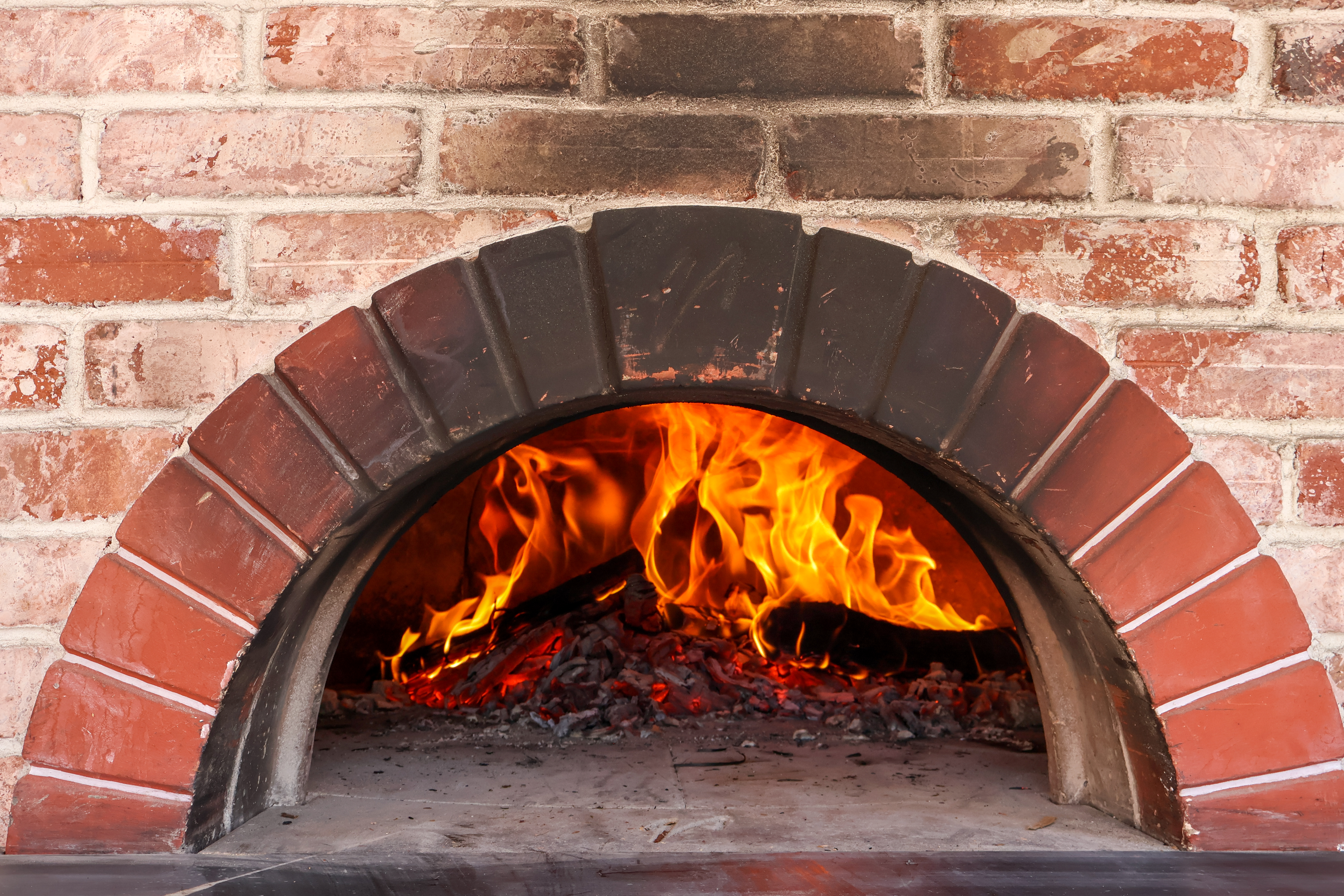 a stone fireplace is next to a brick wall