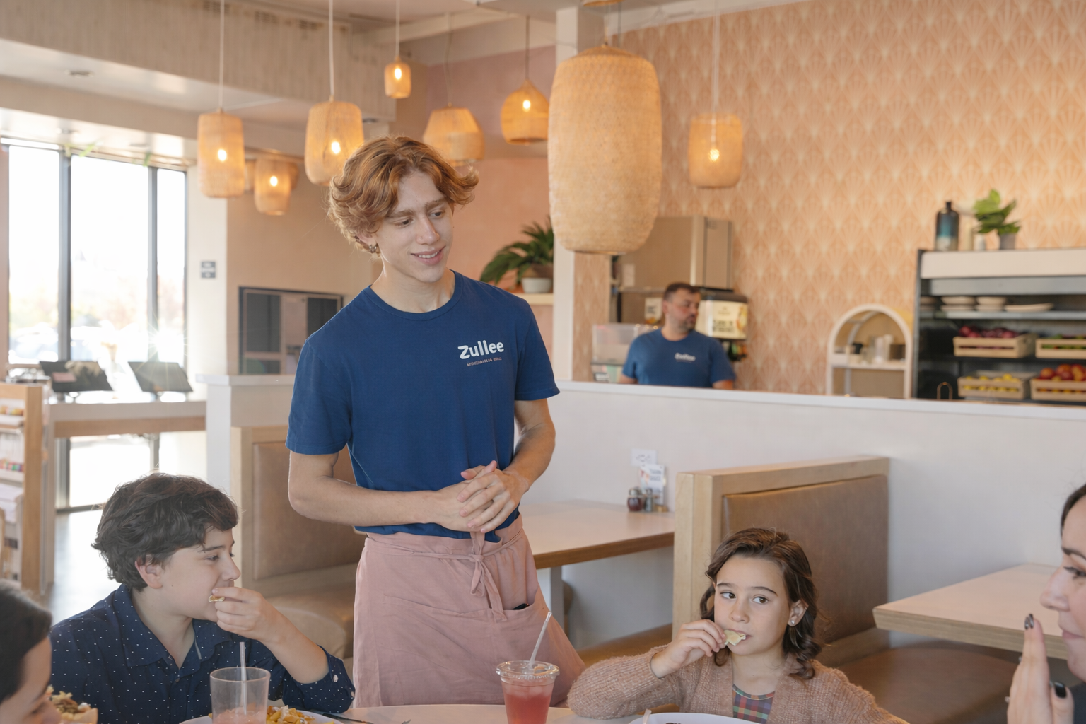 a man standing next to a group of people eating at a table