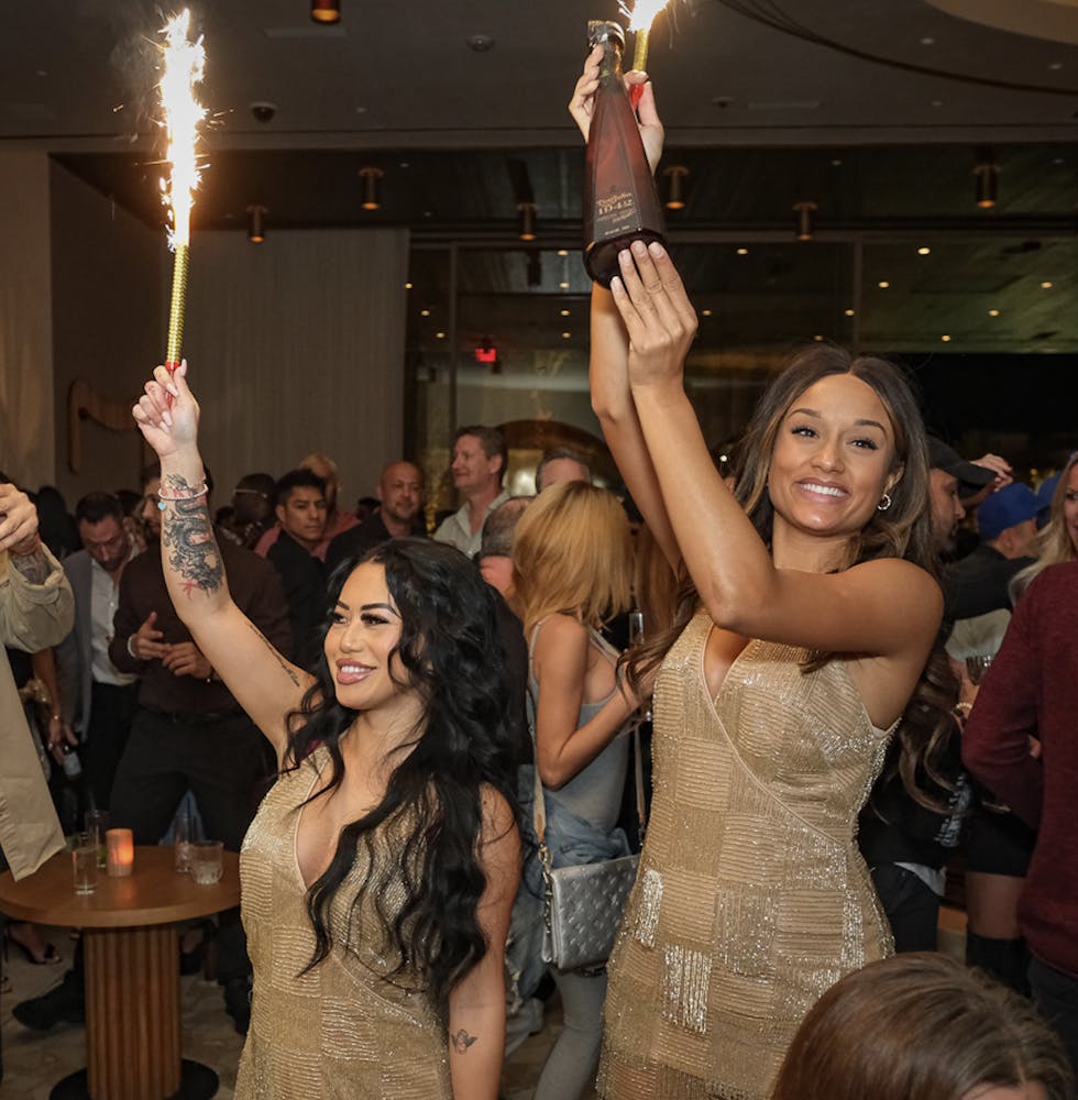 two cocktails servers at the Las Vegas bar, Bel-Aire holding sparklers at a table inside