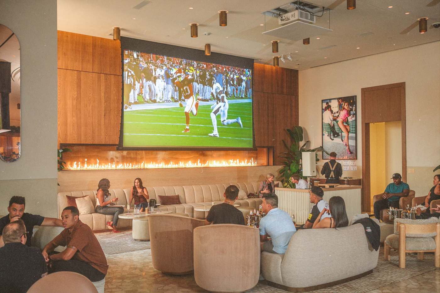 Guests watching Monday Night Football at Bel-Aire Lounge Las Vegas with a giant projection screen and modern lounge seating.