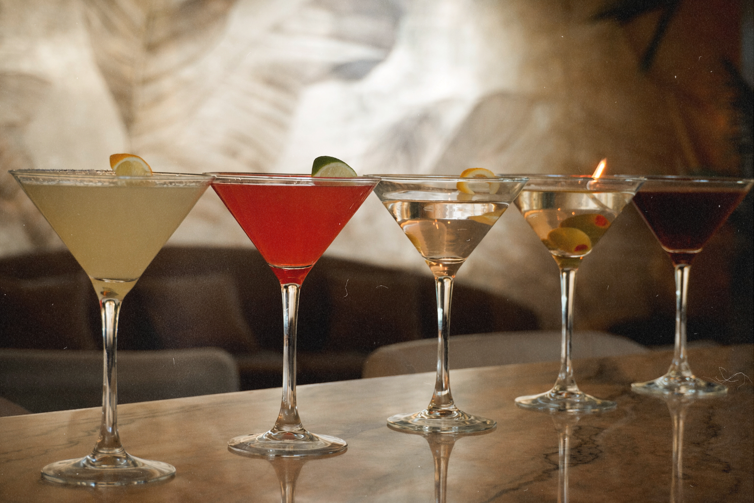 Assorted handcrafted martinis lined across a marble table inside Bel-Aire Lounge, a stylish local lounge in Las Vegas featuring elevated cocktails and nightlife ambiance.