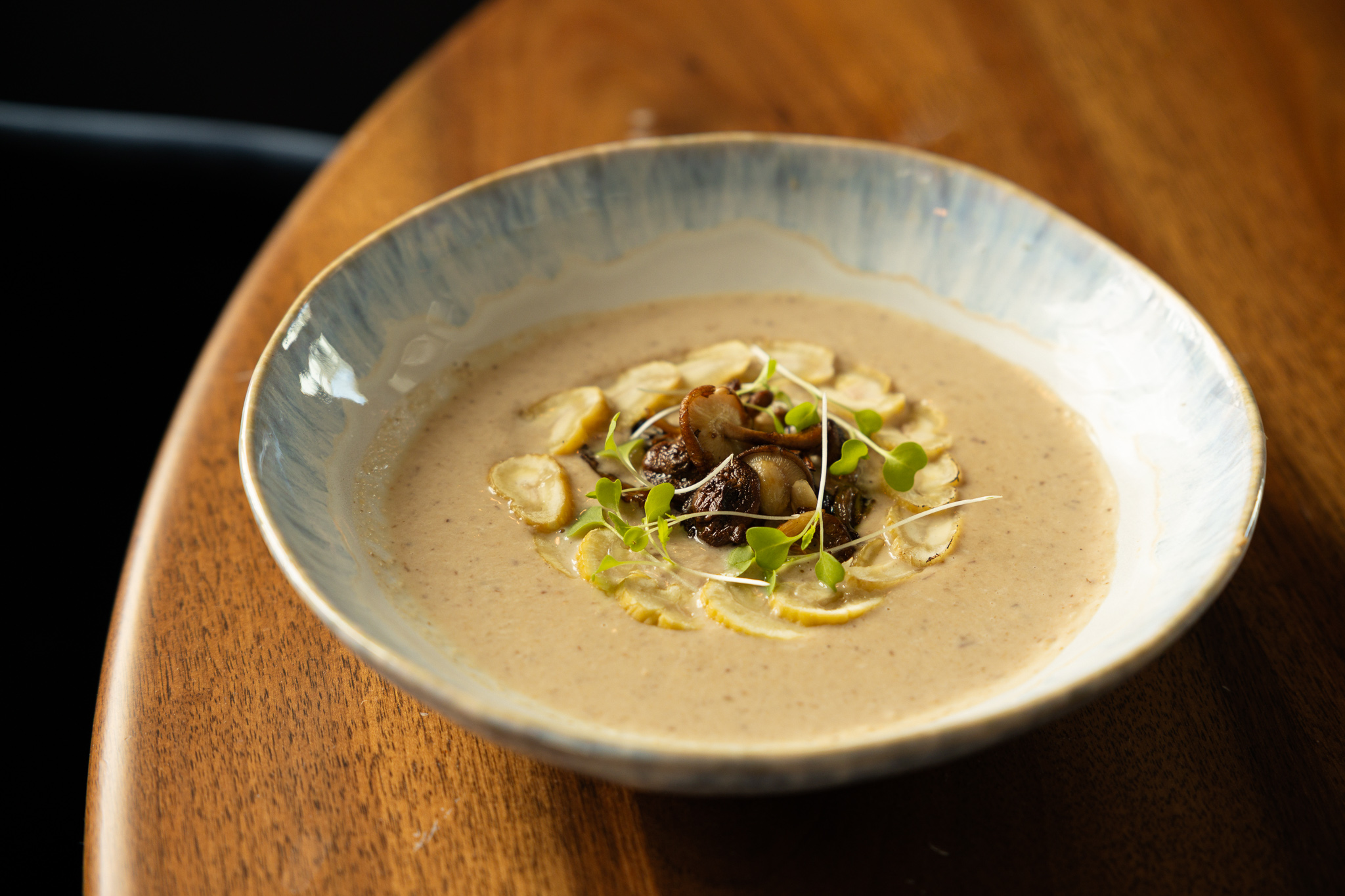 a bowl of soup with mushrooms and sprouts