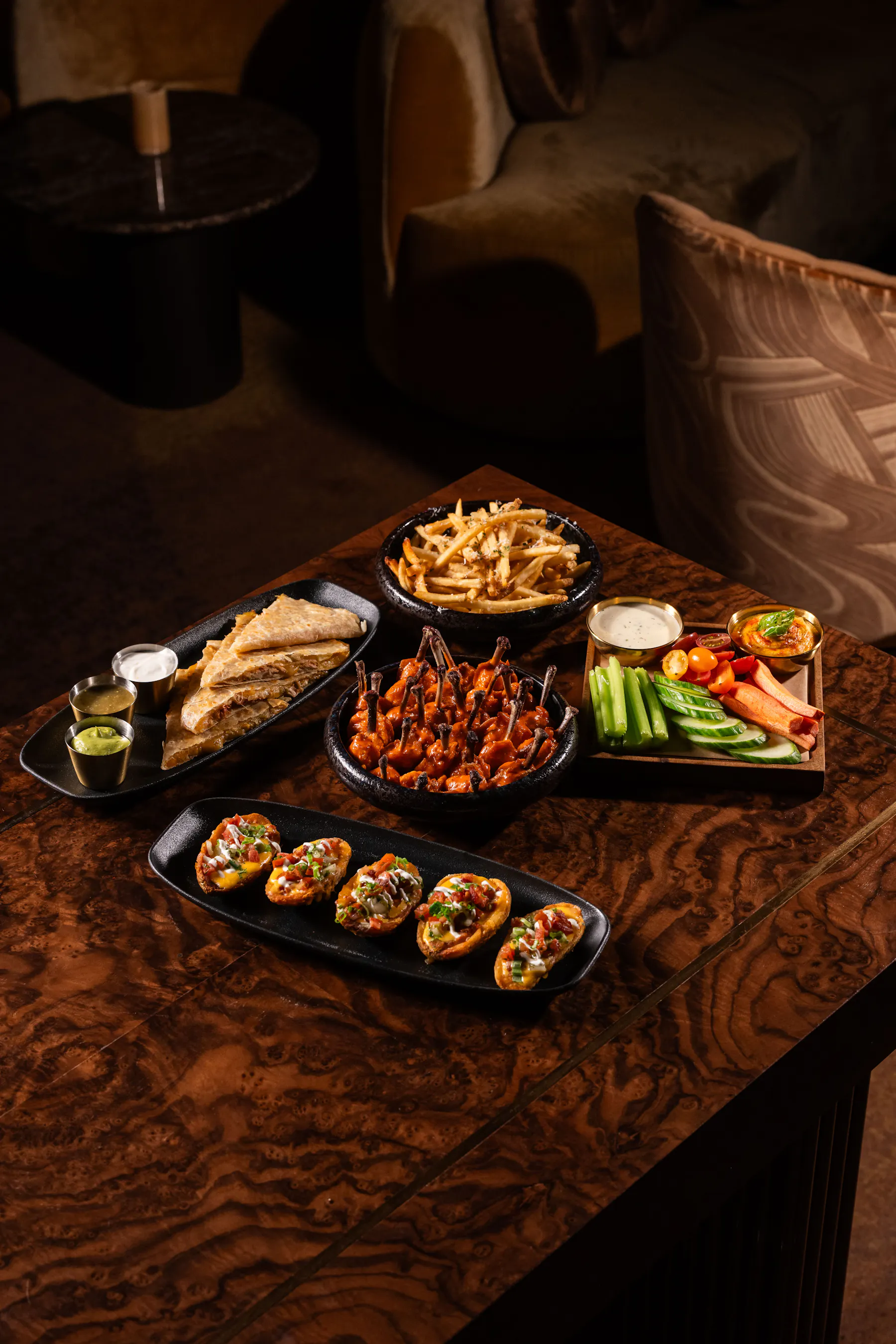 Clique game-day spread with wings, loaded potato skins, quesadillas, fries and fresh vegetables