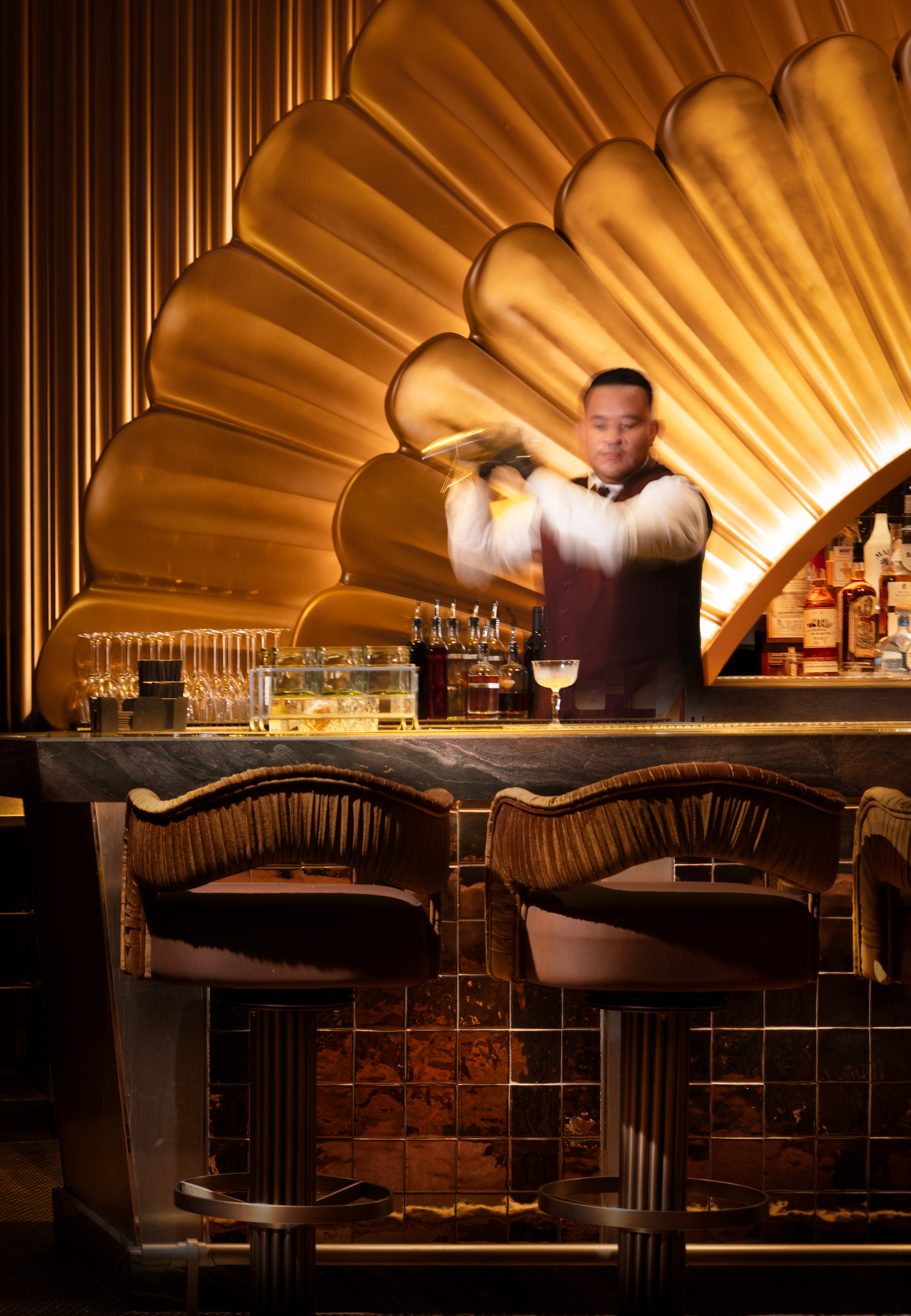 a man in a white shirt and apron holding a drink