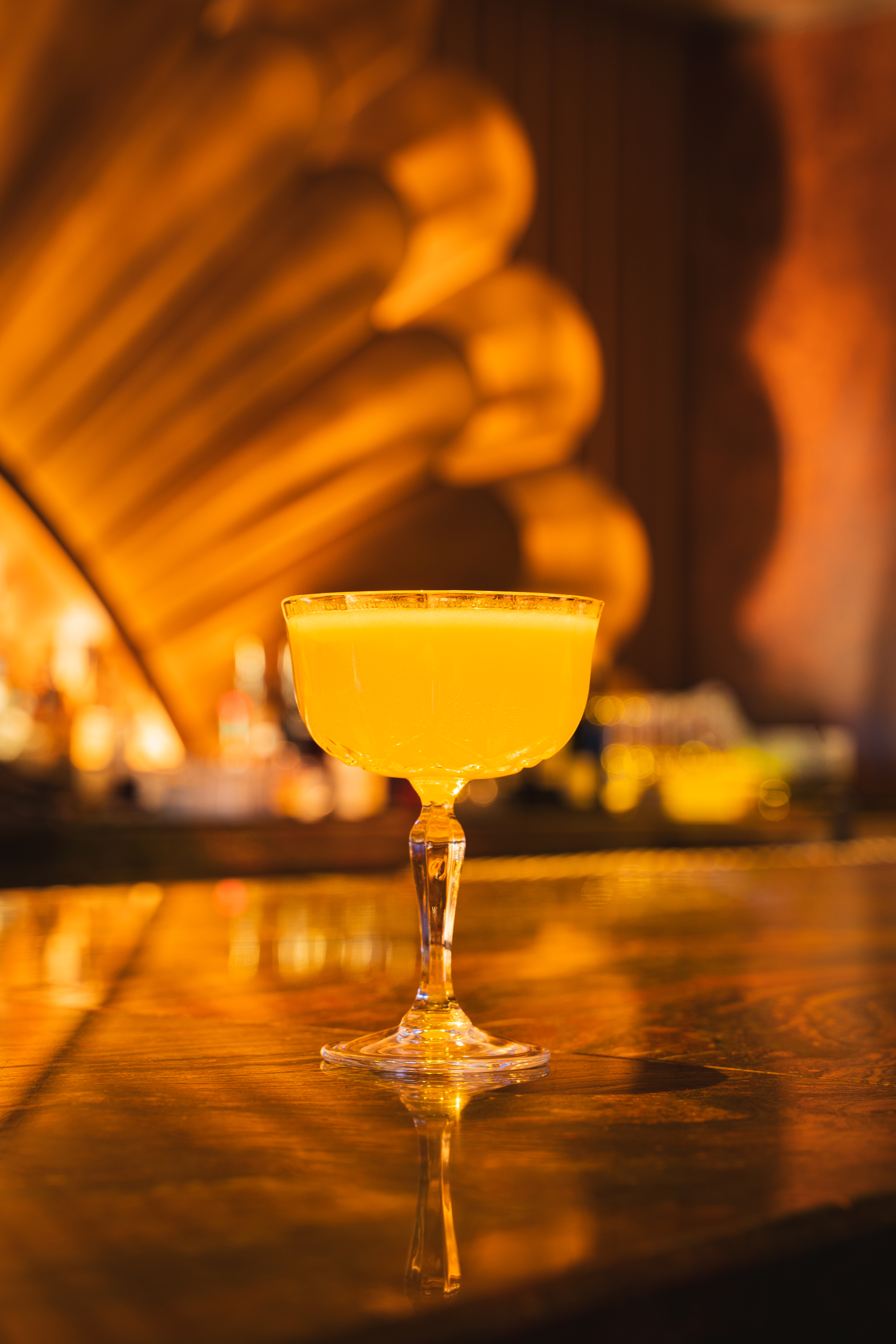 Golden cocktail with an egg white foam top served at the bar at Clique, a Las Vegas cocktail lounge at The Cosmopolitan