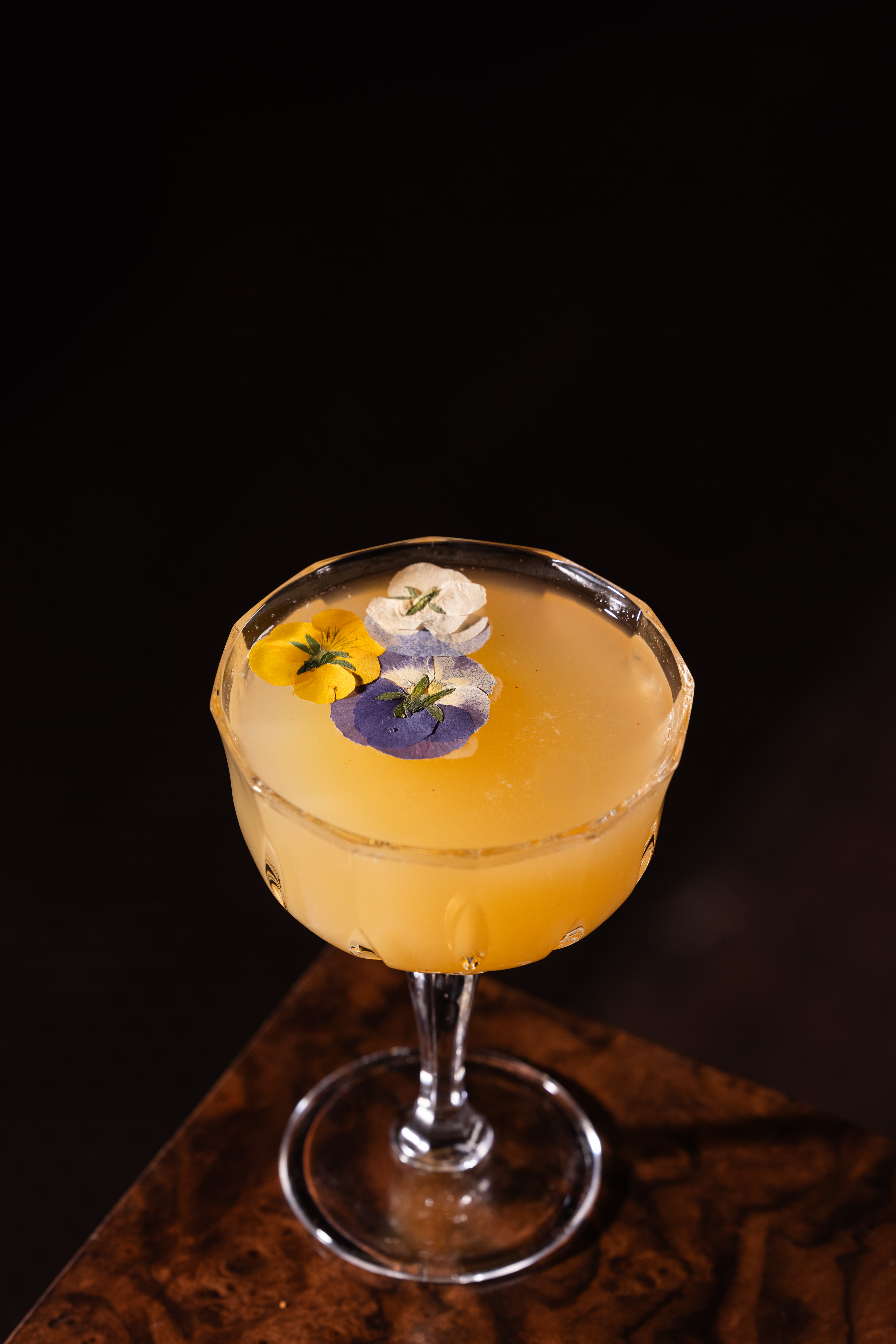 Craft cocktail with edible pressed flowers in a coupe glass at Clique, a Las Vegas cocktail lounge at The Cosmopolitan