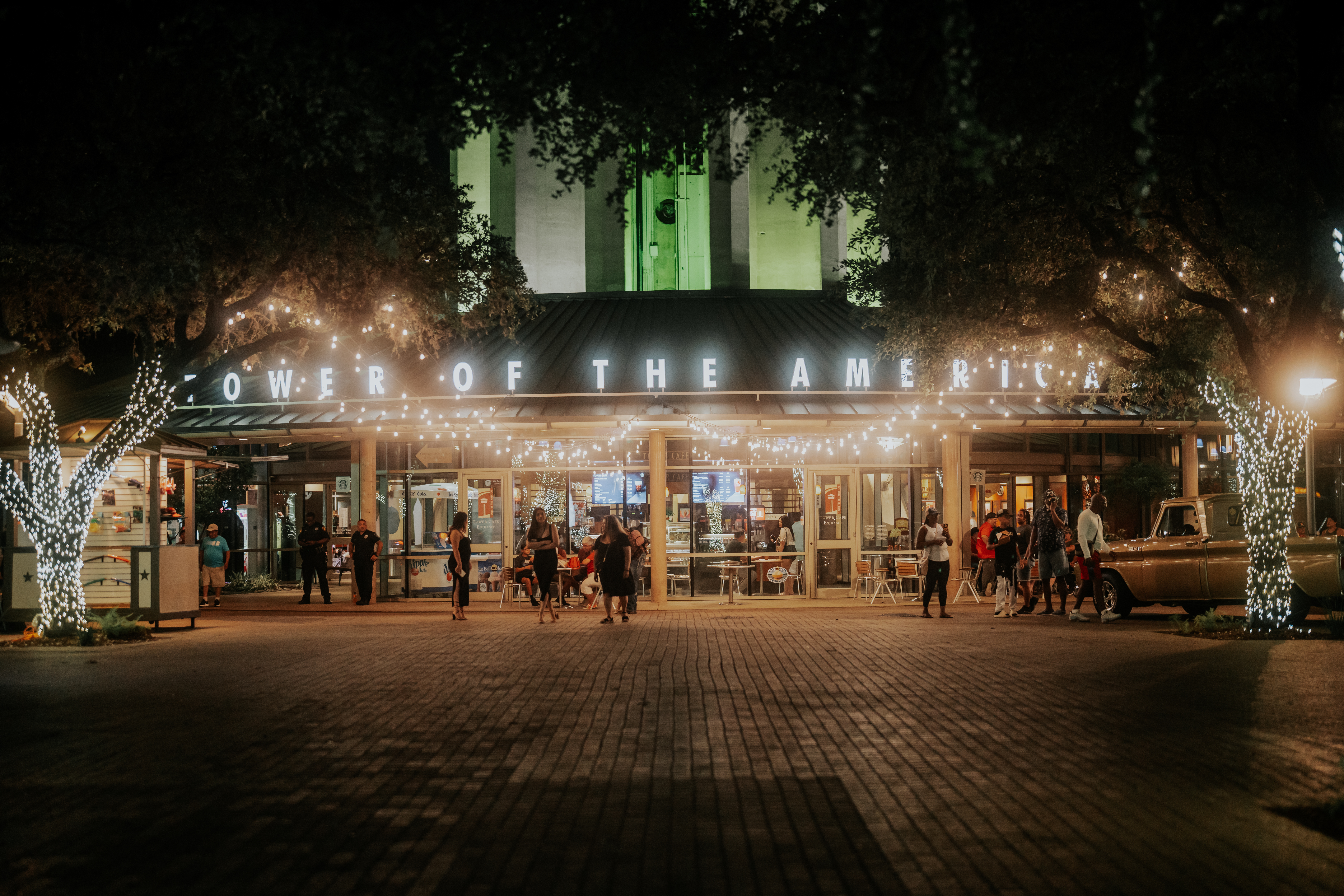 a group of people in front of a clock tower lit up at night