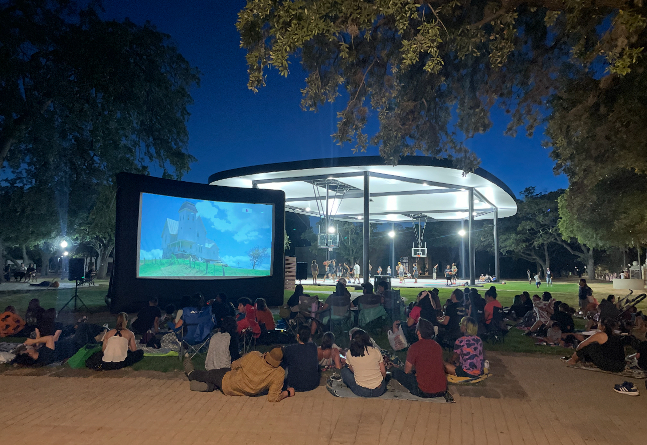 a group of people sitting on the ground watching a movie