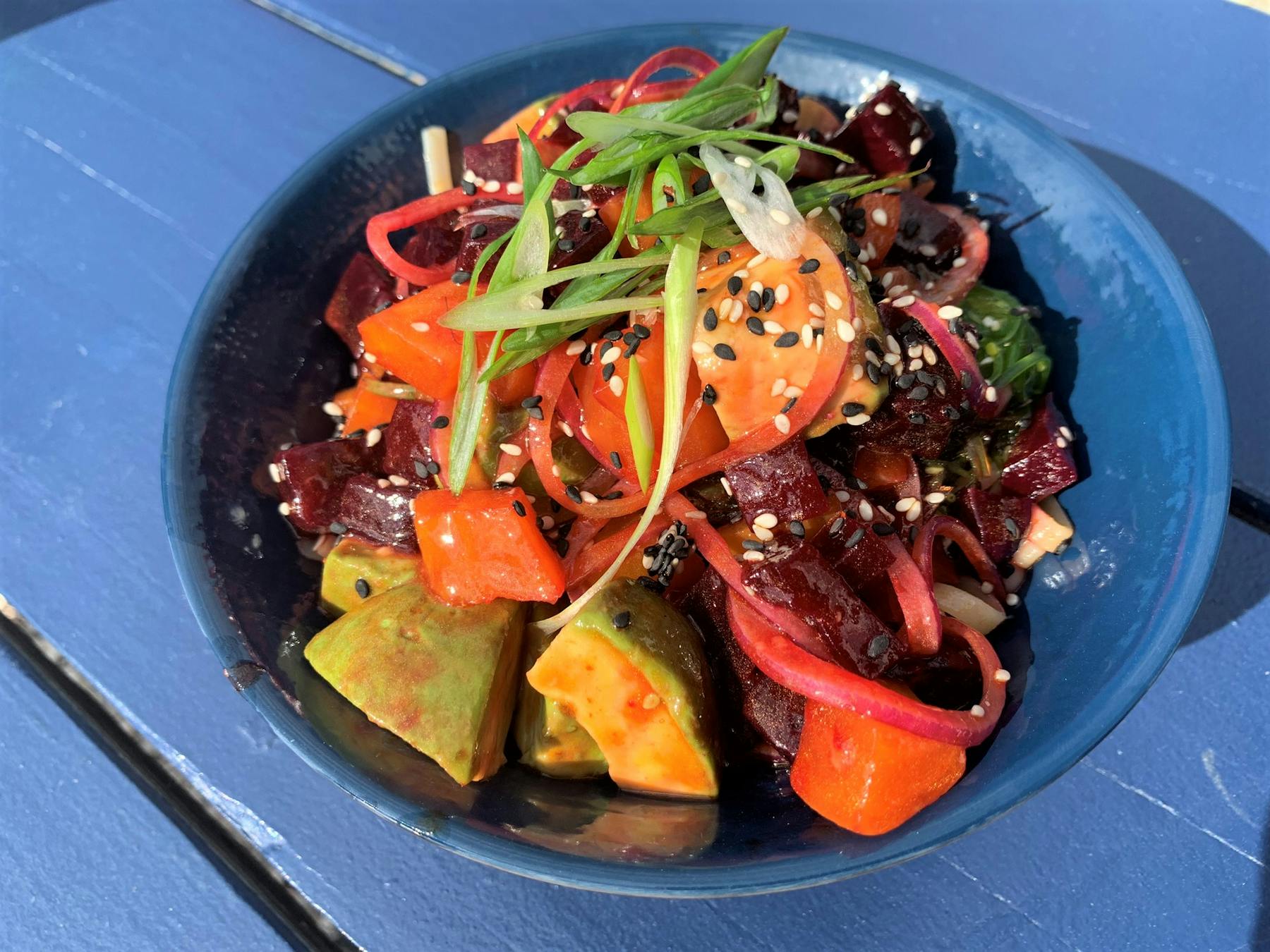 a blue bowl filled with meat and vegetables on a plate