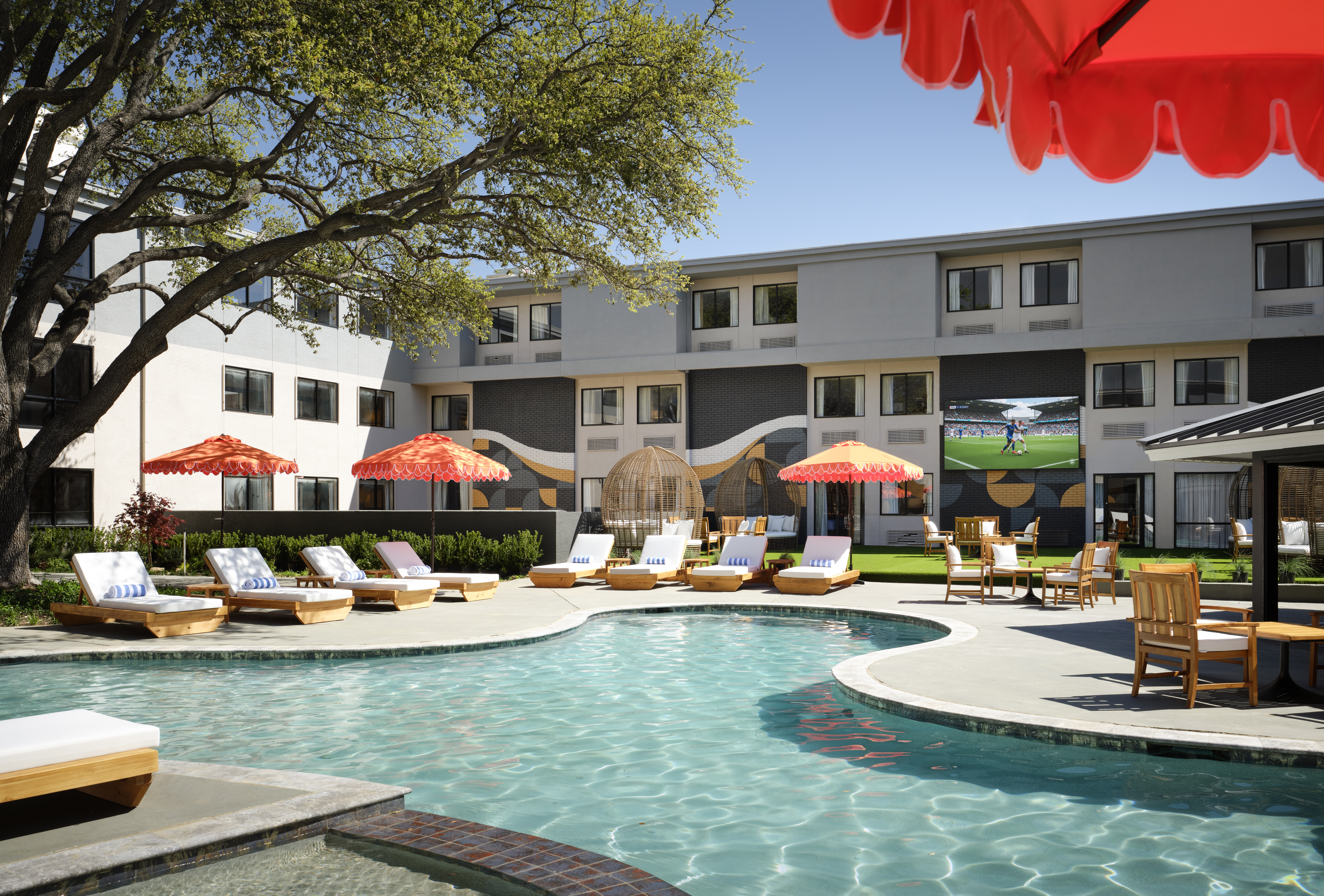 a pool with chairs and umbrellas in front of a building