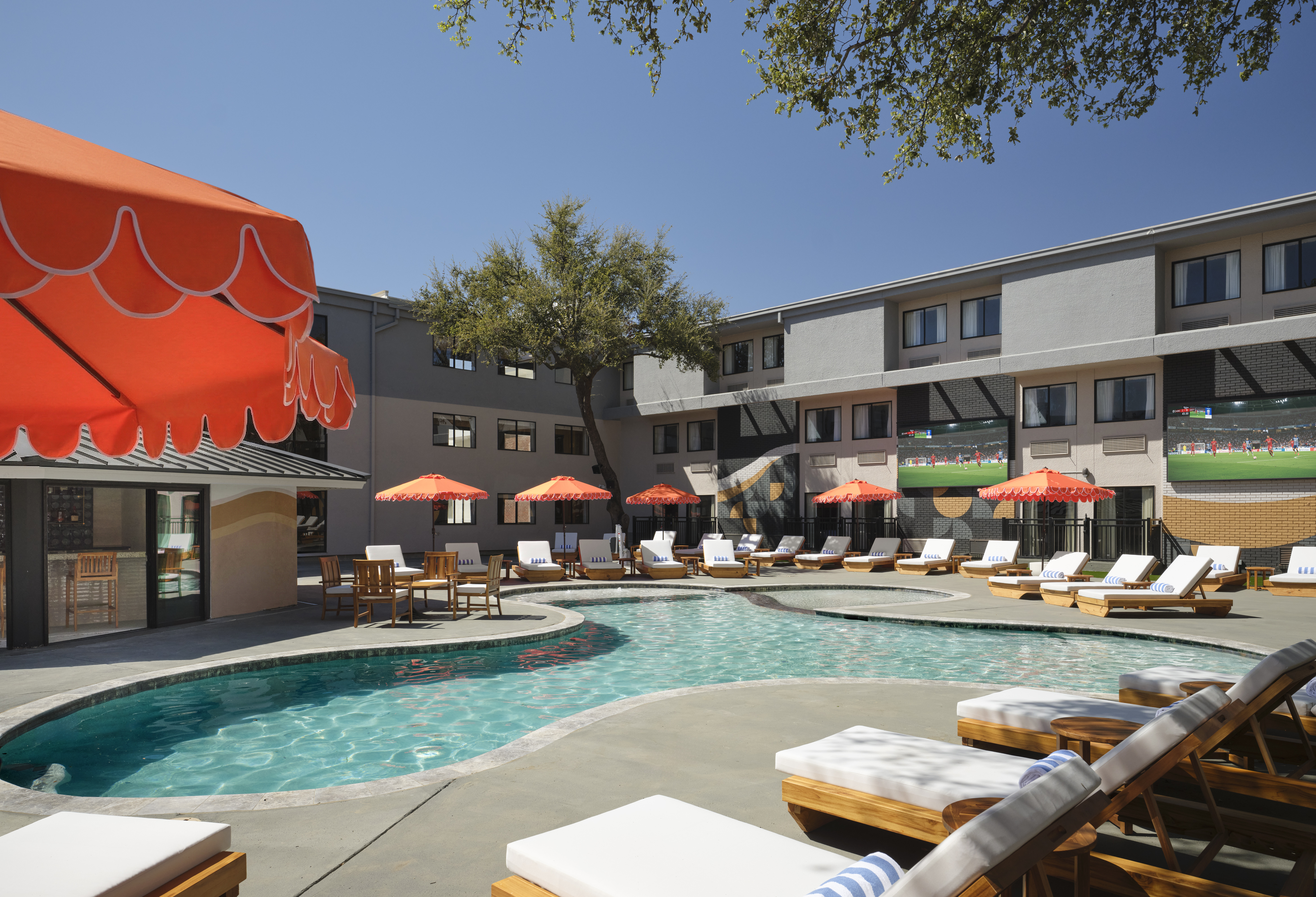a pool with chairs and umbrellas in front of a building