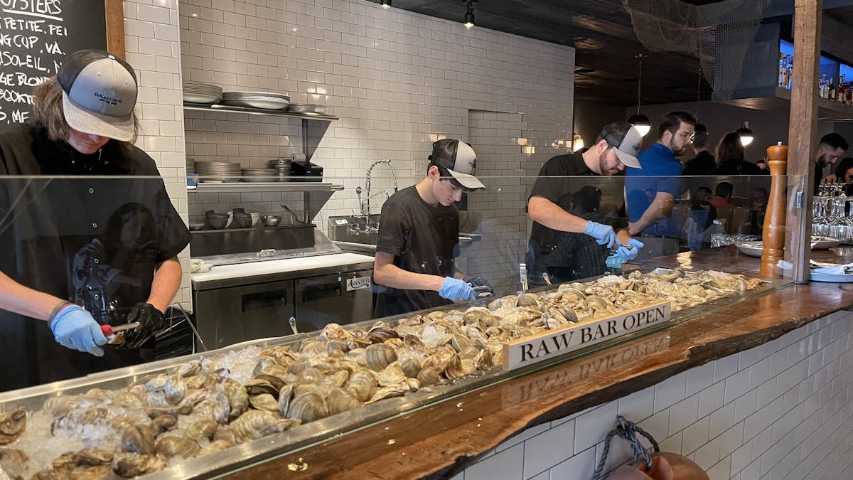 a group of people performing on a counter preparing food