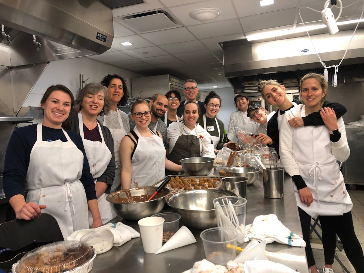 a group of people standing in a kitchen preparing food