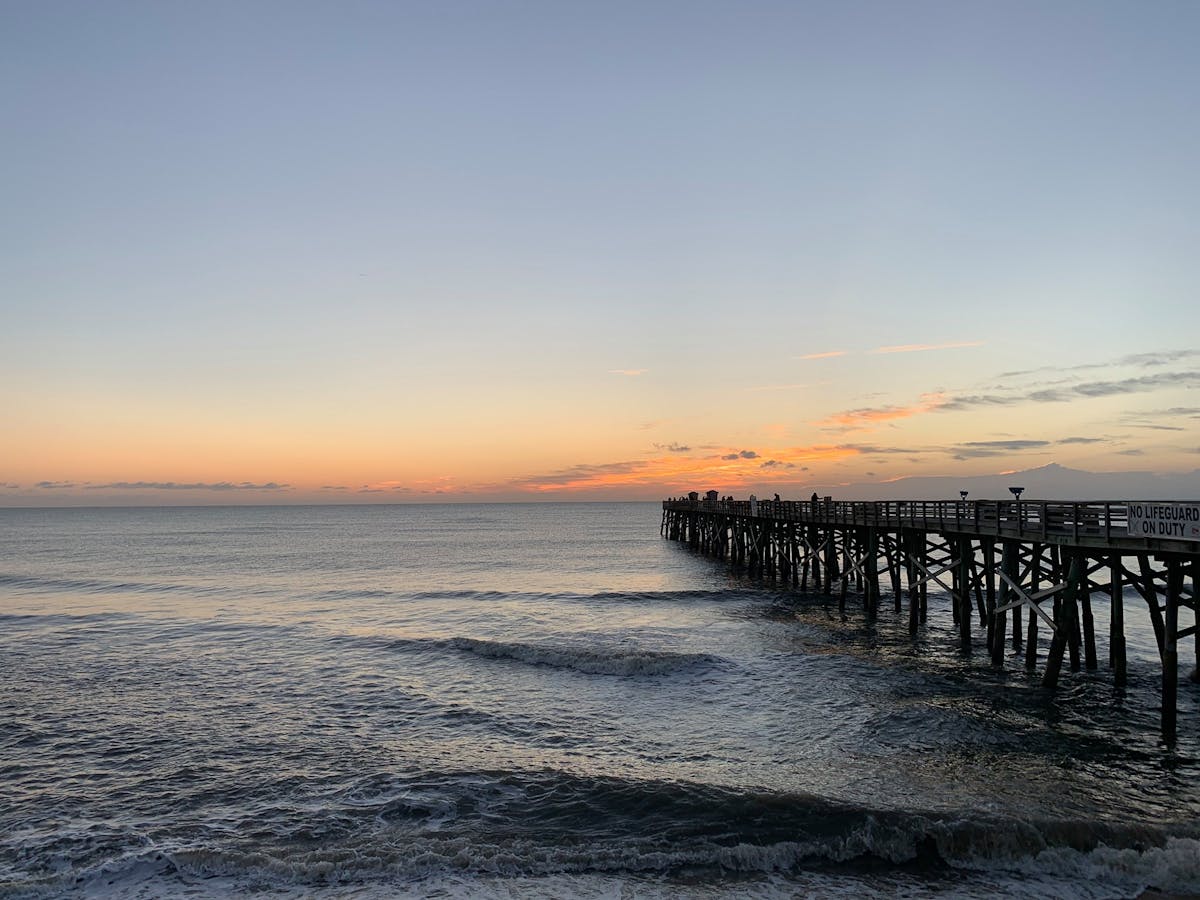 a beach with a pier in front of a body of water