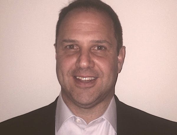 a man wearing a suit and tie smiling at the camera