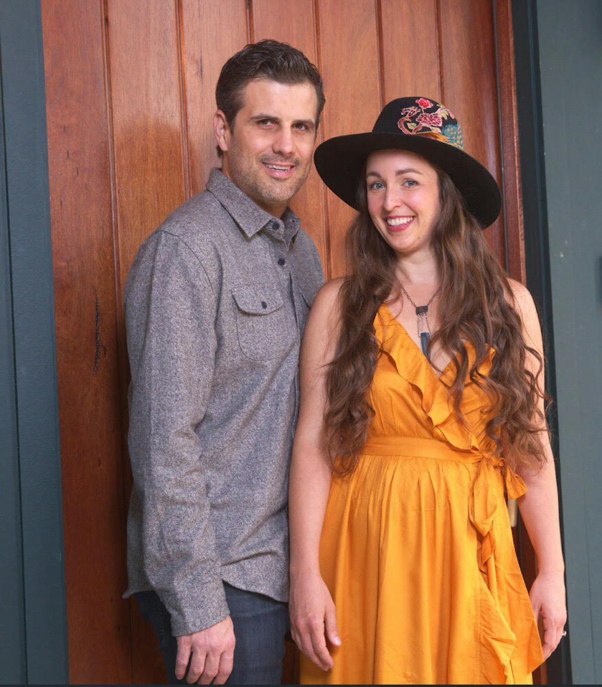 a man and a woman standing in front of a yellow wall