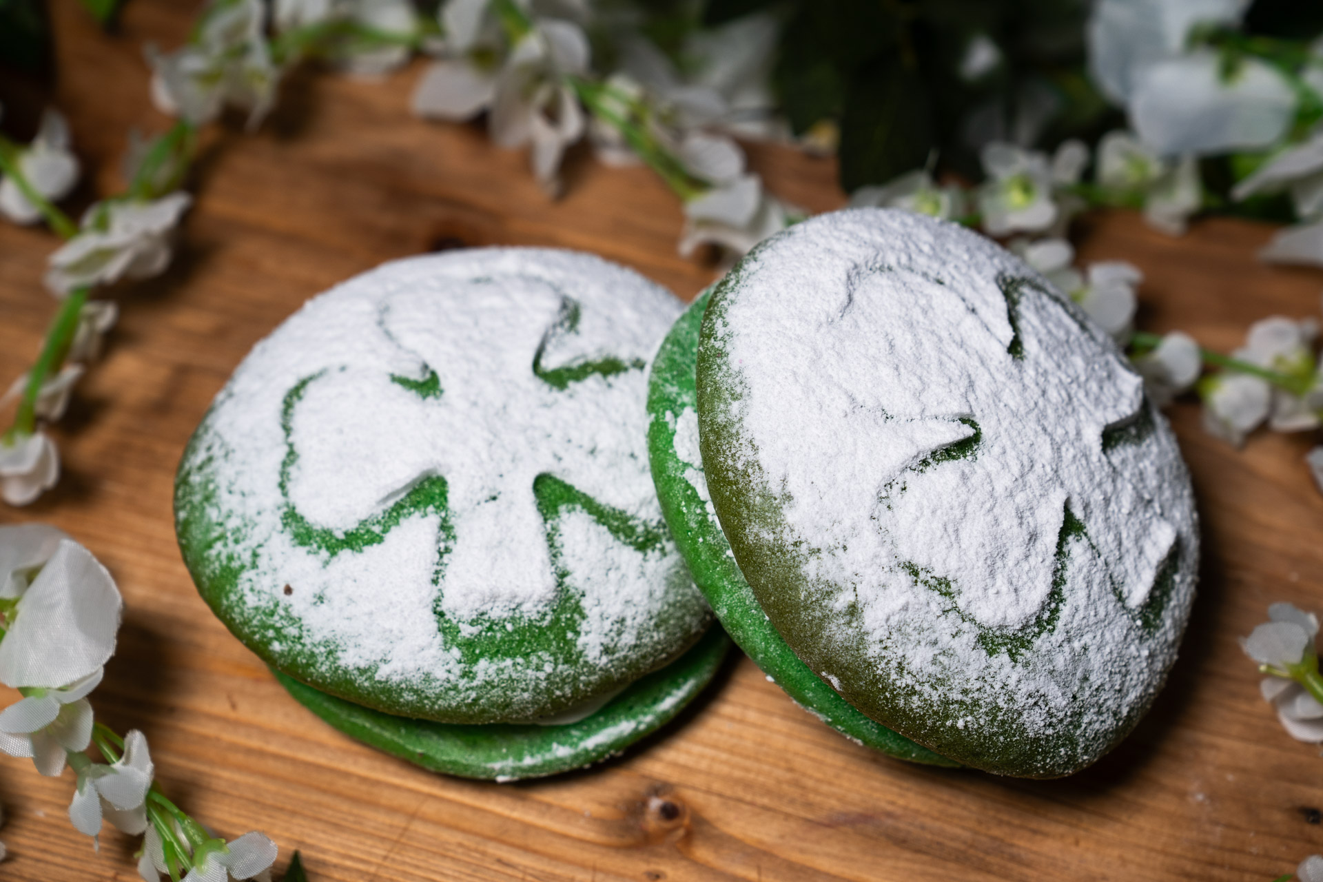 two green cookies with a shamrock design on top