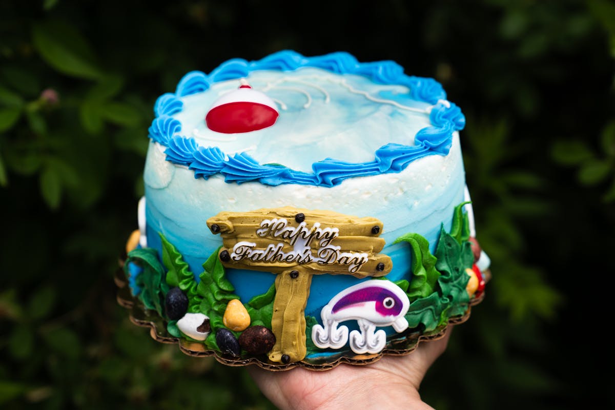 a hand holding up a birthday cake