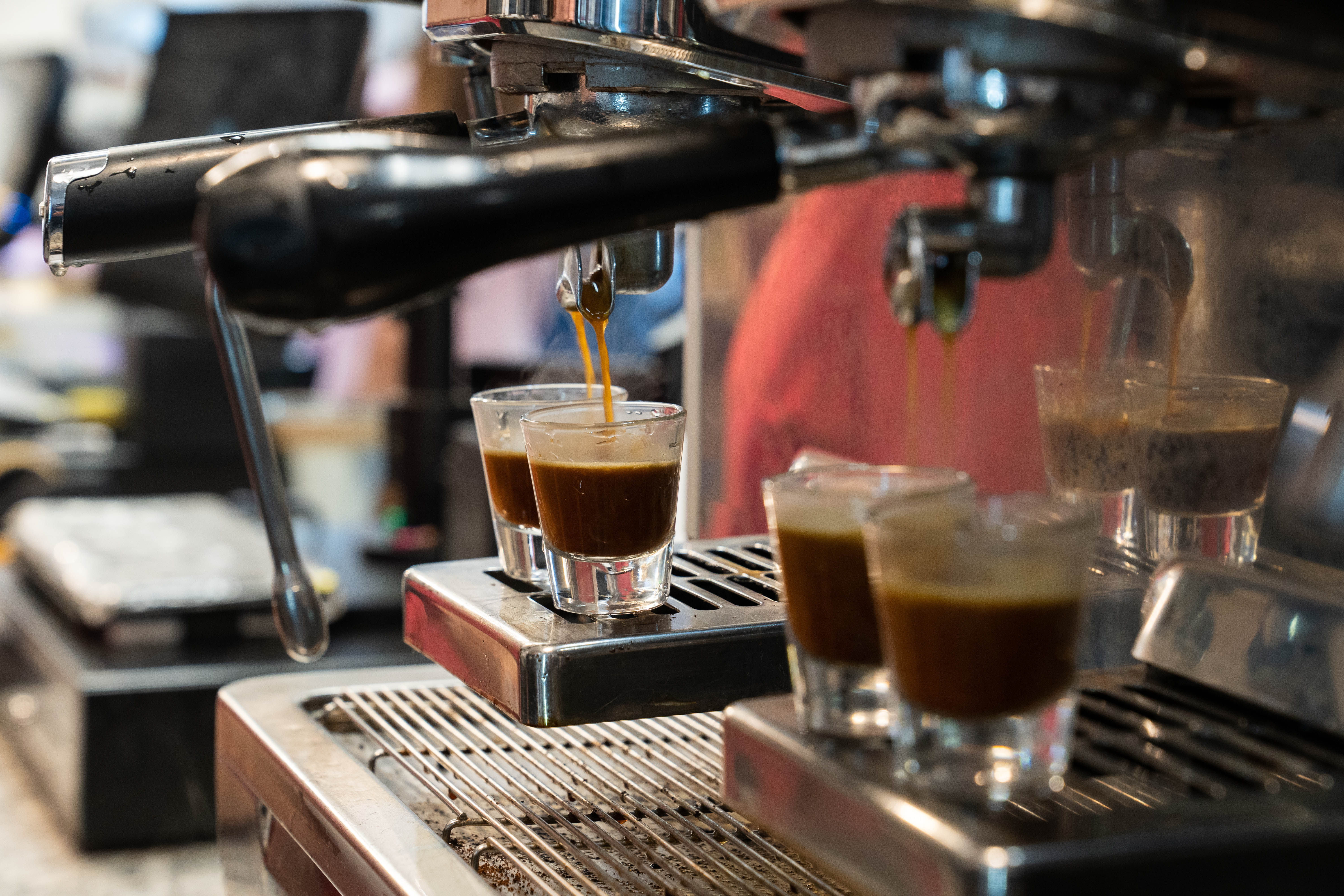 a coffee machine pouring liquid into shot glasses