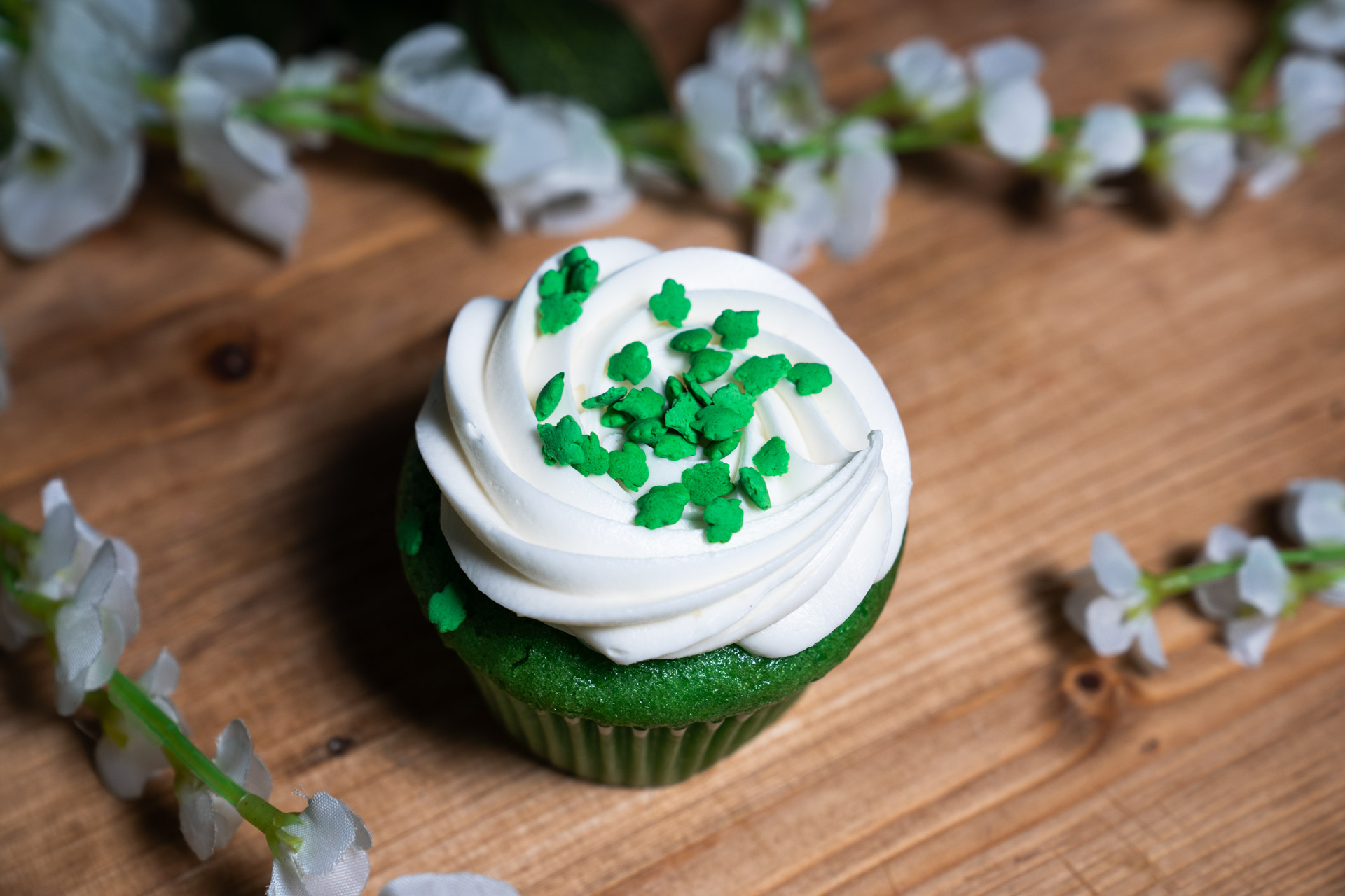 a cupcake with green frosting and white sprinkles