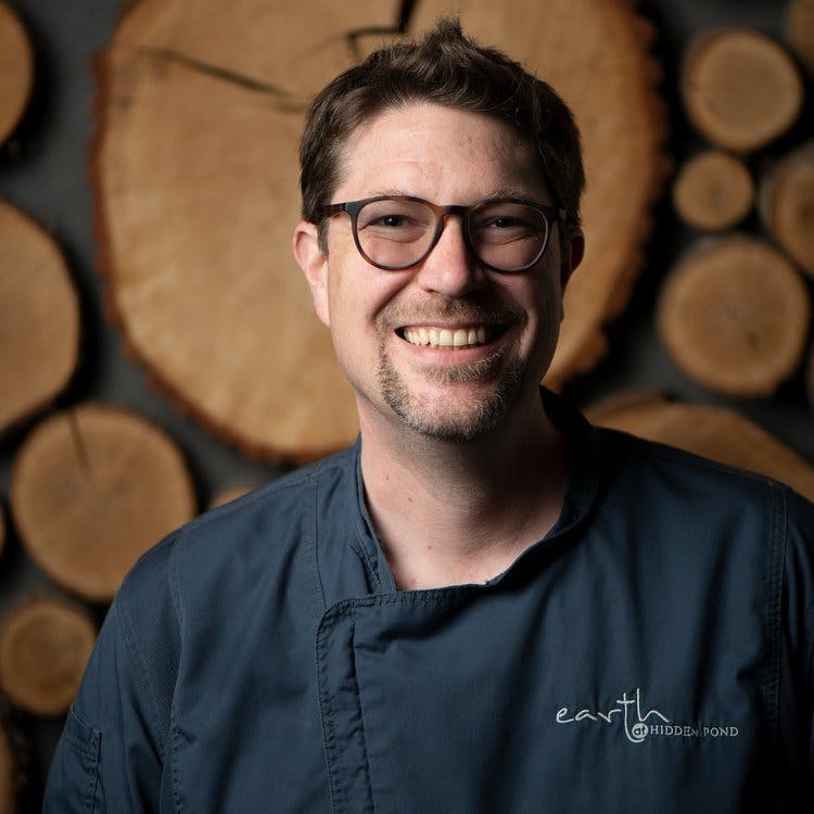 a man wearing glasses and smiling at the camera