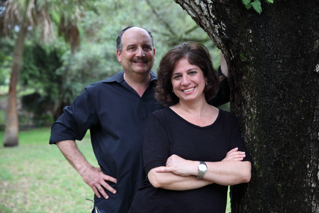 a man and a woman standing in front of a tree